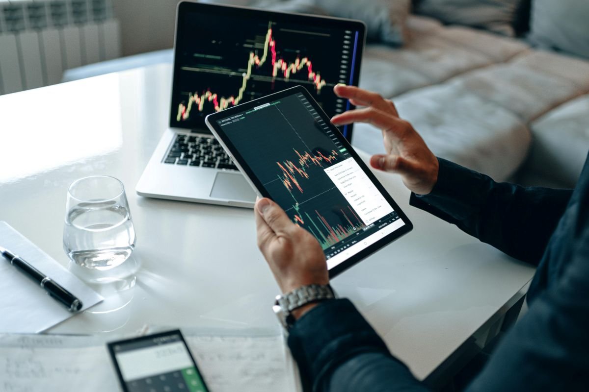 Primeiros Investimentos Após Reserva: Pessoa analisando gráficos de ações e renda fixa para multiplicação de patrimônio.